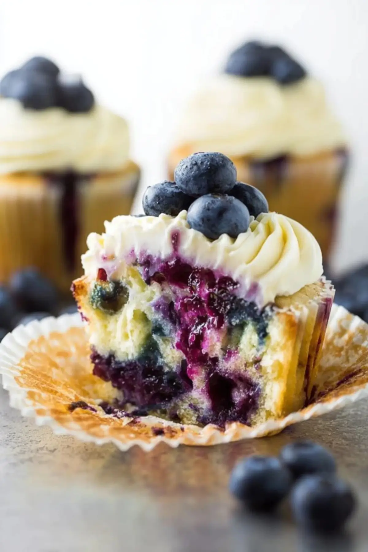 White Chocolate Blueberry Cheesecake Cupcakes with frosting and blueberry drizzle