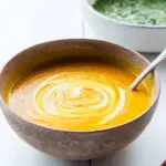 Carrot Soup with Chermoula in a bowl with fresh herbs