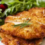 Fried chicken breast with crispy breading and fresh arugula topping
